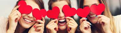 3 women holding cut out hearts on their eyes